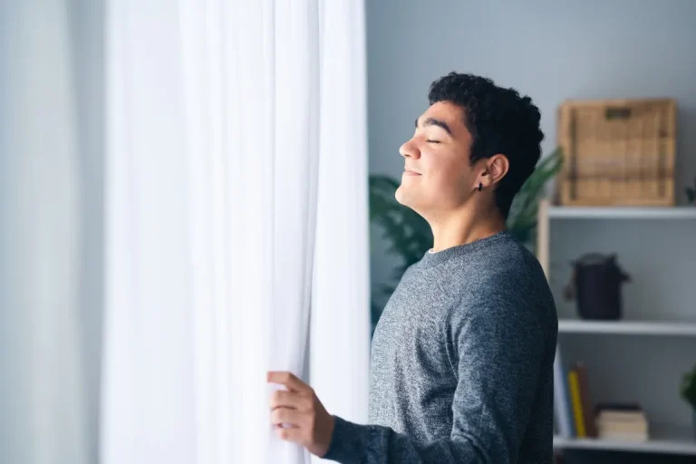 man breathing deep indoors beside the window